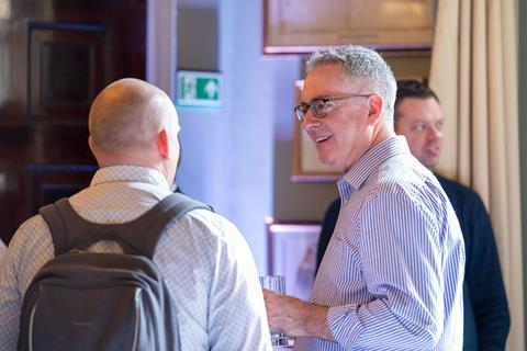 Two male attendees engage in a light-hearted discussion while waiting to join Insurance Times' Fraud Charter roundtable.